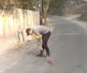 Bhabinkamtibmas O’o Bersihkan Pasir di Jalan yang Bahayakan Pengguna Jalan